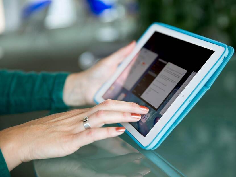 Hand met roodgelakte nagels tikt met vinger op het scherm van een ipad.