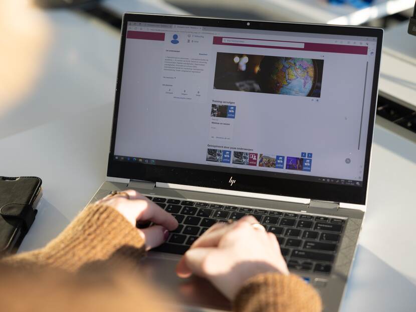 Laptop with homepage new learning portal on screen and two hands of user resting on keyboard